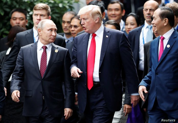 U.S. President Donald Trump and Russia's President Vladimir Putin talk as Vietnam's President Tran Dai Quang looks on, during the family photo session at the APEC Summit in Danang, Vietnam