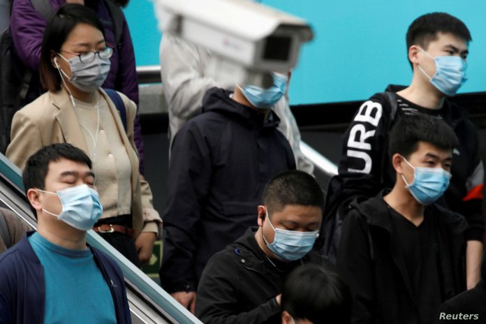 People wearing face masks are seen near a surveillance camera inside a subway station during morning rush hour in Beijing