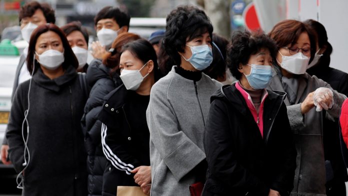 People wearing masks stand in a line to buy face masks in front of a drug store amid the rise in confirmed cases of the novel coronavirus disease of COVID-19 in Daegu