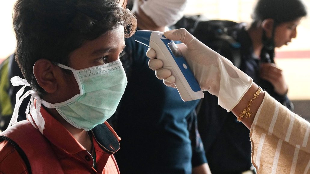 A government health worker in Kerala checks a boy’s temperature