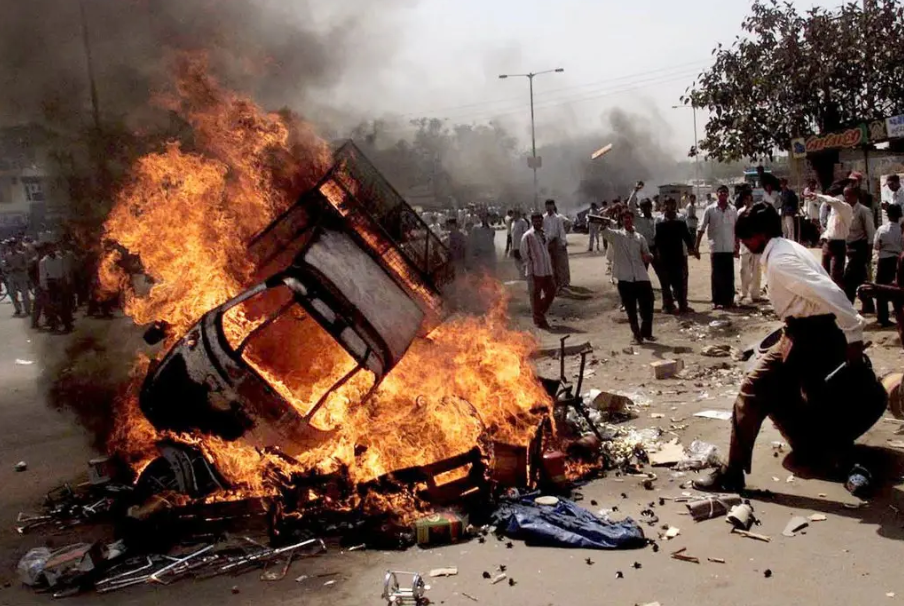 Vehicles on fire in Ahmedabad, India, on Feb. 28, 2002, the day 69 Muslims, mostly women and children, died in a compound set ablaze by thousands of Hindu men armed with stones, iron rods and bombs.Credit...Manish Swarup/Associated Press